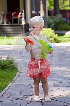 Portrait of blonde baby boy playing with water toy
