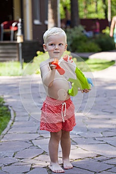 Portrait of blonde baby boy playing with water toy