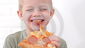 Portrait blonde boy Eating cheese Pizza Smiling close up .Happy Child chewing slice pizza Indoors. Unhealthy junk fast