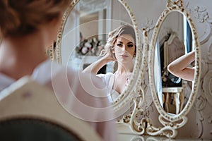 Portrait of blonde bride woman in a white lingerie sitting near mirror, fashion beauty portrait