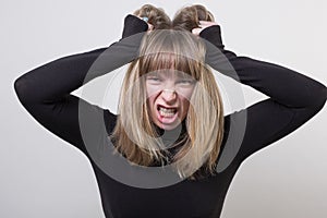 Portrait of a blonde caucasian female pulling her hair hysterically photo