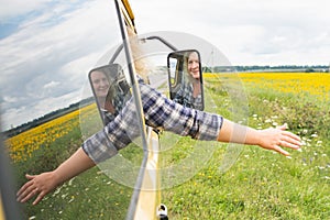 Portrait of blonde Caucasian woman through car window with sunflower field on background