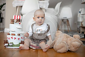 Portrait of blonde child. Indoors home child birthday party, baby with big blue eyes sitting on floor