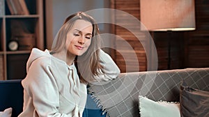 Portrait blonde domestic woman relaxing sitting on comfortable couch at evening living room interior