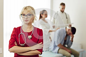 Portrait of a blonde female doctor in a red uniform with a stethoscope.