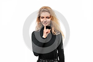 Portrait of blonde girl keeping finger at her mouth, saying Shh, Hush, Tsss. Silence and secret concept, isolated