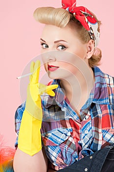 Blonde girl on pink background. Lady holds cigarette in hands with rubber gloves. Housewife smoking break.