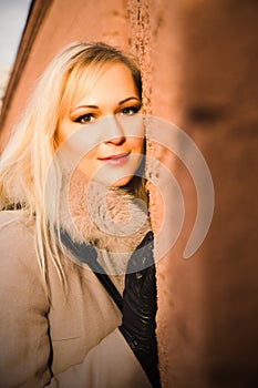 Portrait of blonde girl in warm coat over a brick wall