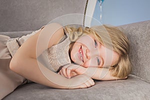 Portrait of blonde little girl lies on a sofa