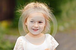 Portrait of blonde little girl of 5 years in a white dress, clos