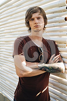 Portrait of blonde man at white bamboo wall