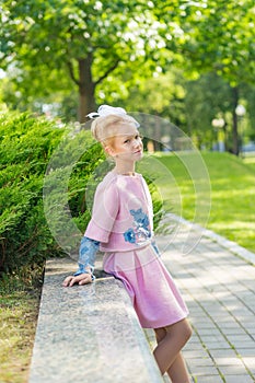 Portrait of a blonde in pink attire in a park outdoors.