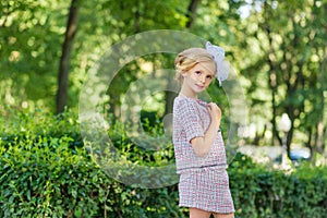 Portrait of a blonde in pink attire in a park outdoors.