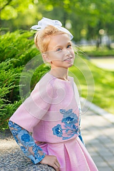 Portrait of a blonde in pink attire in a park outdoors.
