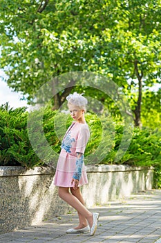 Portrait of a blonde in pink attire in a park outdoors.