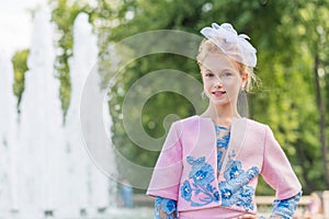 Portrait of a blonde in pink attire in a park outdoors. Vintage