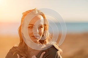 Portrait blonde sea cape. A calm young blonde in an unbuttoned khaki raincoat stands on the seashore, under the raincoat