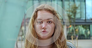 Portrait of a blonde teenage girl with freckles looking seriously at camera. Portrait of a young student