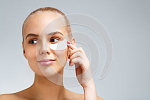 Portrait of a blonde woman applying undereye mask photo