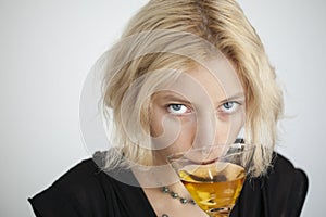 Blonde Young Woman with Beautiful Blue Eyes Drinks a Martini