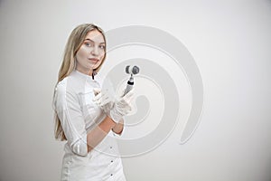 Portrait of blonde woman dermatologist with dermatoscope in white lab coat and white gloves on the white background