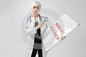 Portrait of blonde woman in doctors costume with a magnetic board in her hands isolated on background