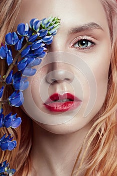 Portrait blonde woman with flower petals on her face closeup, bright makeup and lipstick. Skin hydration, face care, antiaging