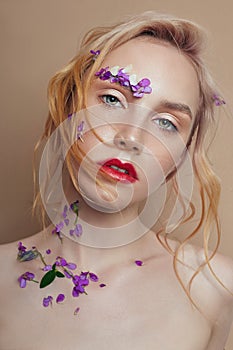 Portrait blonde woman with flower petals on her face closeup, bright makeup and lipstick. Skin hydration, face care, antiaging
