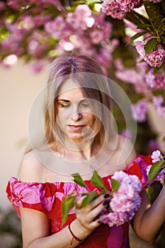 portrait of a blonde woman next to a blooming Japanese cherry tree