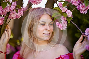 portrait of a blonde woman next to a blooming Japanese cherry tree