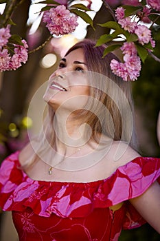 portrait of a blonde woman next to a blooming Japanese cherry tree