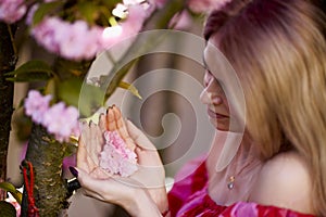 portrait of a blonde woman next to a blooming Japanese cherry tree