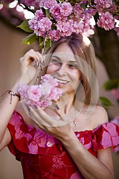 portrait of a blonde woman next to a blooming Japanese cherry tree