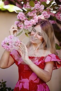 portrait of a blonde woman next to a blooming Japanese cherry tree