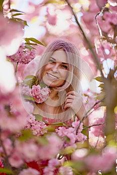 portrait of a blonde woman next to a blooming Japanese cherry tree