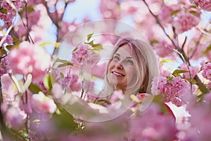 portrait of a blonde woman next to a blooming Japanese cherry tree