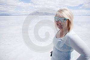 Portrait of blonde woman smiling wearing sunglasses at Utah`s Bonneville Salt Flats on a sunny day