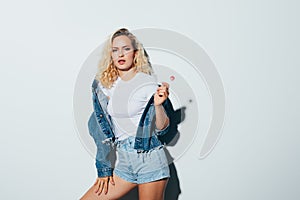 Portrait of blonde woman wearing holding candy on white background