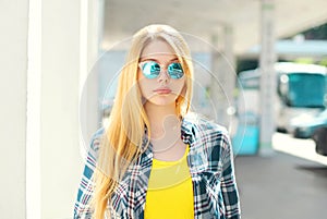 Portrait blonde young girl wearing a checkered shirt and sunglasses
