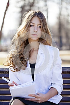 Portrait of blonde young schoolgirl sitting on the bench