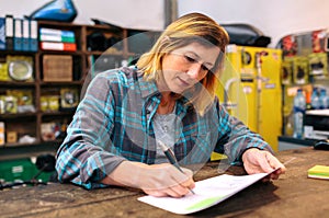 Portrait of blonde young woman checking orders received by ecommerce shop