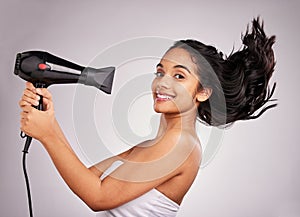 Portrait, blow dry and hair with a woman in studio on a gray background holding a beauty appliance. Salon, smile and