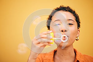 Portrait, blowing bubbles and woman in studio for fun, playful or freedom of expression on yellow background. Bubble