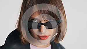 Portrait of blue eyed girl with bob hair and red lips wearing sunglasses isolated on white background