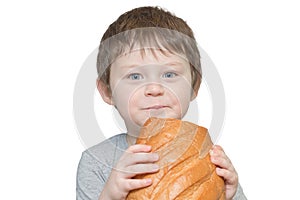 Portrait of a blue-eyed little boy holding a large loaf of bread in his hands. Will eat it. Horizontal photo, isolated on white