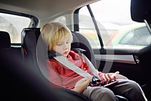 Portrait of a bored little boy sitting in a car seat. Safety of children