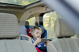 Portrait of a bored little boy sitting in a car seat. Safety of transportation of children