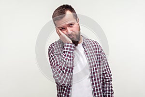 Portrait of bored young bearded man leaning on hand with dull lazy face expression. white background