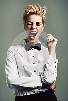 Portrait, bow tie or crazy woman with fashion, vintage clothes and classy aesthetic on grey background. Screaming, edgy