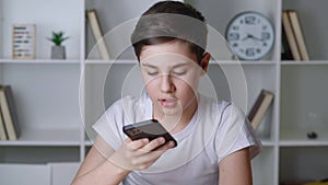 Portrait of a boy of 13 years old sending a voice message on his smartphone. Teenager male using app on his mobile phone